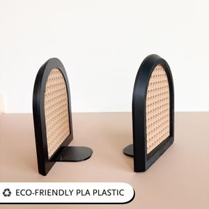 May include: Two black bookends with a woven rattan-style center. The bookends have a curved top and a flat base. The text "ECO-FRIENDLY PLA PLASTIC" is at the bottom.