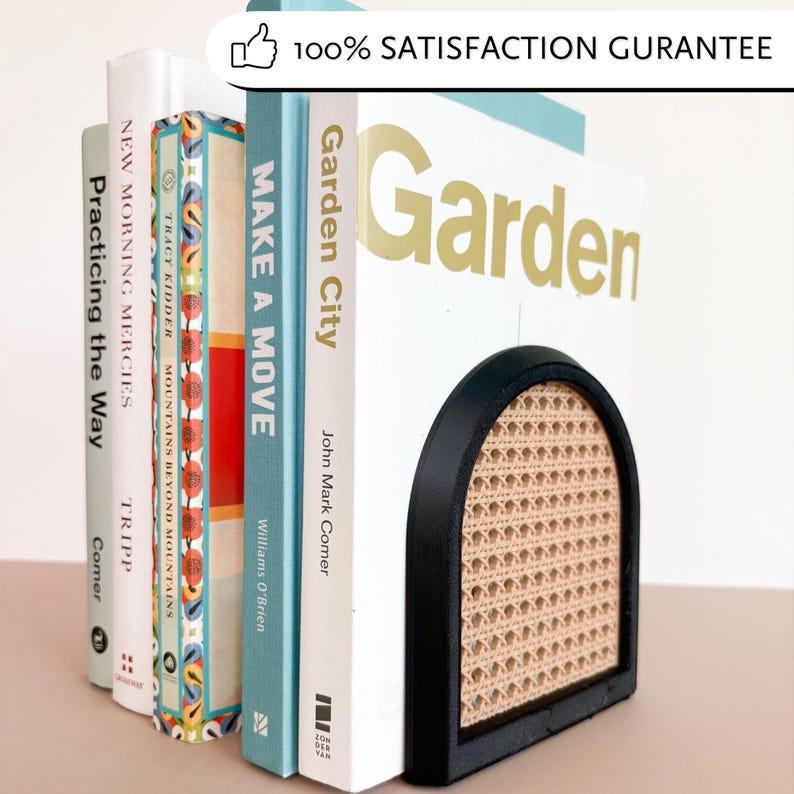 May include: A black and tan bookend with a woven cane design supports a row of books. The books have titles like "Garden City" and "Make a Move." The bookend has an arched shape and a sturdy base, providing a decorative and functional way to organize books.