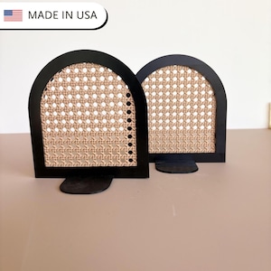 May include: Two black arched bookends with woven cane inserts. The bookends have a rectangular base and a semi-circular top. The text "MADE IN USA" is in the upper left corner.