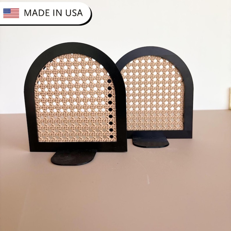 May include: Two black arched bookends with woven cane inserts. The bookends have a rectangular base and a semi-circular top. The text "MADE IN USA" is in the upper left corner.