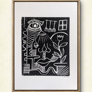 Op de afbeelding: Zwart-wit linoleumsnede in een houten lijst. Het kunstwerk toont abstracte vormen, waaronder een oog, een fles, een neus en een bloem in een pot. De prent heeft een minimalistische stijl met gedurfde lijnen en een getextureerd uiterlijk.