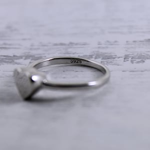 May include: A silver heart-shaped ring with the inscription "S925" on the band.