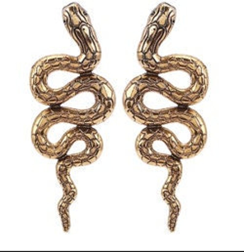 K&ouml;nnte beinhalten: Ein Paar goldfarbene Schlangenohrringe. Die Schlangen sind eingerollt und haben eine strukturierte Oberfl&auml;che.