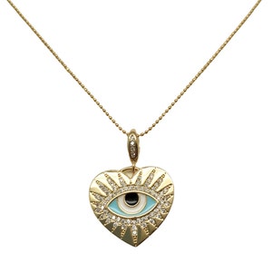 May include: A gold heart-shaped pendant necklace with a blue evil eye charm and clear crystal accents.