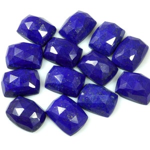 Peut inclure: Douze cabochons de lapis-lazuli bleu foncé, chacun de forme rectangulaire facetté. Les pierres ont une taille légèrement irrégulière et brute et sont disposées en un tas lâche.