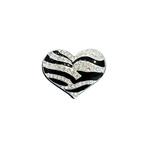 May include: A black and white zebra-print heart-shaped brooch with clear rhinestones.