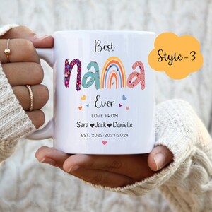 May include: White ceramic mug with the text "Best Nana Ever" in colorful letters with a rainbow and hearts. The text "Love from Sera Jack Danielle Est. 2022/2023/2024" is below the main text. The mug has a yellow cloud with the text "Style-3" in black.