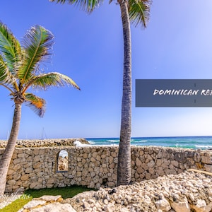 May include: A stone wall with a small window opening overlooking a blue ocean with a palm tree in the foreground. The text "DOMINICAN REPUBLIC" is written in white on a gray background.