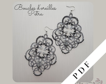 Op de afbeelding: Een paar zilveren oorbellen met zwarte en witte kralen, die een delicaat bloemmotief vormen. De oorbellen zijn gelabeld met "Boucles d'oreilles Petra" en "PDF".
