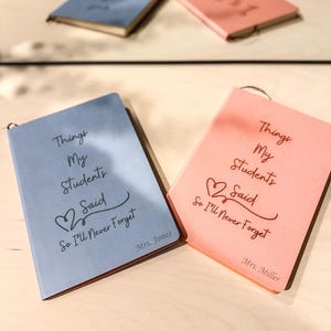 Peut inclure: Deux carnets, l'un bleu et l'autre rose, avec le texte "Things My Students Said So I'll Never Forget" et les noms "Mrs. Jones" et "Mrs. Miller" en bas.