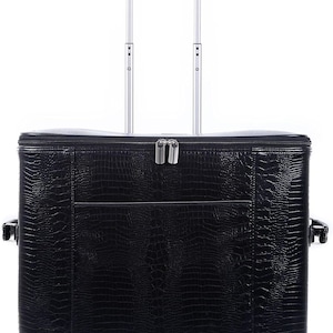 May include: Black rolling suitcase with a textured, crocodile-like pattern. Features a telescoping handle, two wheels, and a front pocket. The suitcase has a zipper closure and silver-colored hardware.