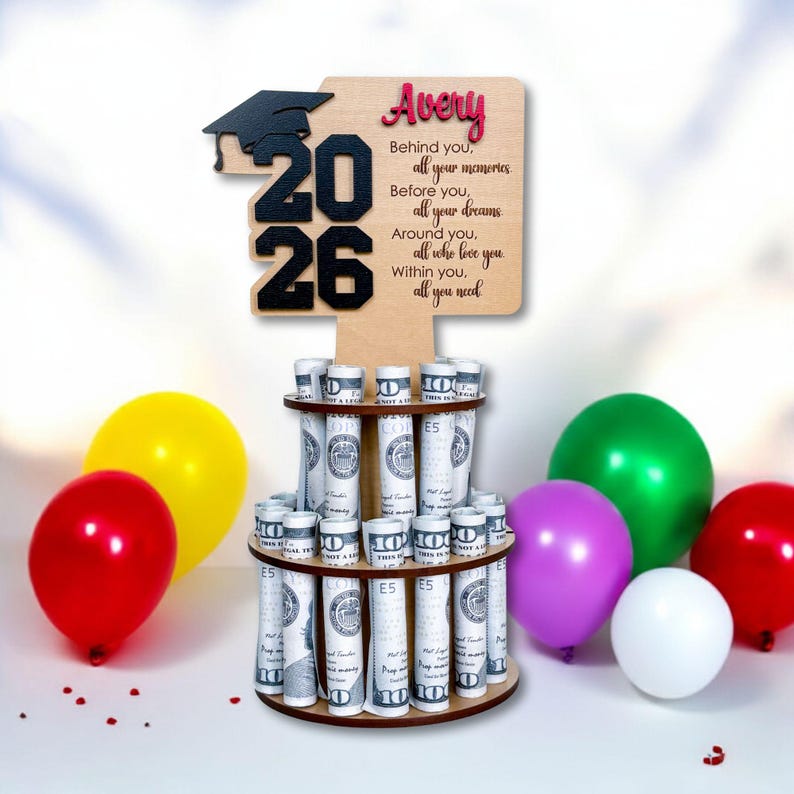 Personalized graduation money holder 2026 in natural wood with black “2026,” graduation cap topper, and custom name. Money tree gift holds rolled US dollar bills for a graduation cash gift. Graduation decorations Class of 2026 for party centerpiece.