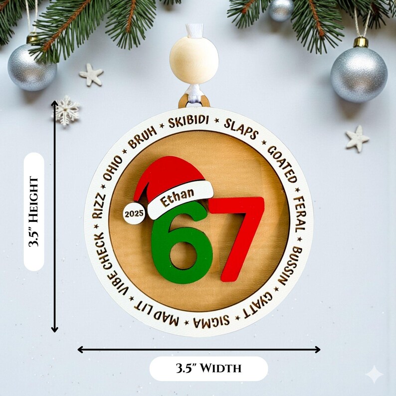 Personalized “67” Gen Z slang Christmas ornament with engraved teen slang words around the border, shown in a flat lay with holiday décor. Ornament features a red and green layered 67 design, Santa hat with custom name, and 2025 year charm. Modern 3.5" x 3.5" round ornament with clean white outer ring and wood-look center. Fun, trendy Christmas gift for teens and tweens, custom stocking stuffer idea.
