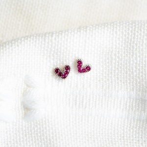 May include: A pair of silver heart-shaped earrings with pink gemstones.
