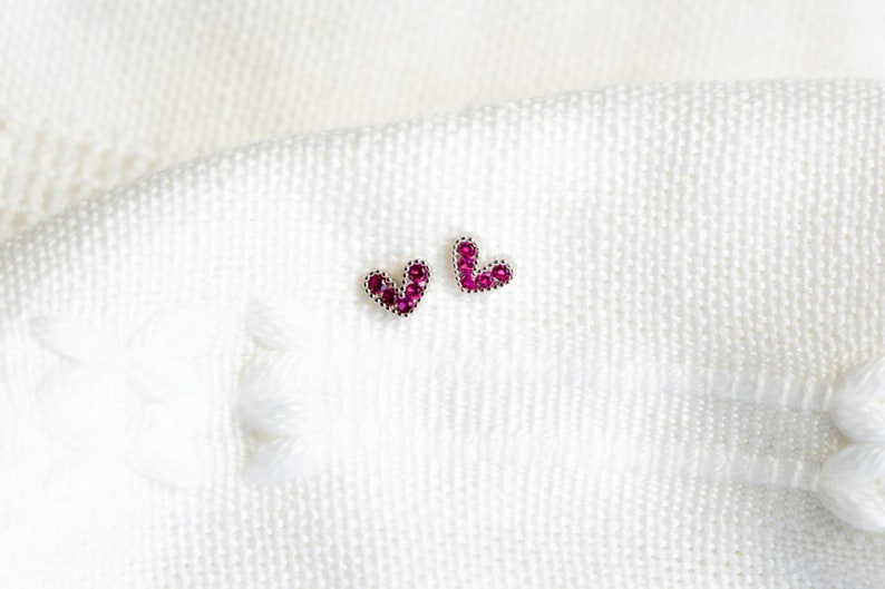May include: A pair of silver heart-shaped earrings with pink gemstones.