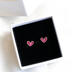 May include: A pair of heart-shaped earrings with pink gemstones set in gold.