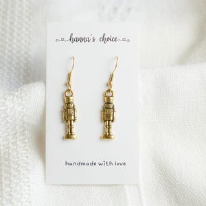 May include: Gold-tone nutcracker dangle earrings with a handmade with love label.