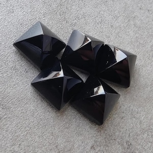 May include: Five black, faceted, pyramid-shaped gemstones.