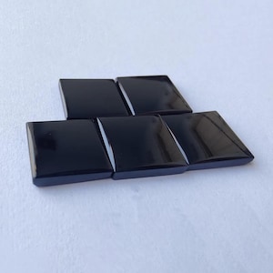 Peut inclure: Cinq pierres polies de forme carrée noires disposées en quinconce.