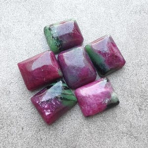 May include: A collection of five polished, rectangular gemstones featuring a vibrant mix of deep magenta, dark red, and forest green colors. Each stone has a smooth, glossy surface with visible natural mineral inclusions and distinct color zoning.