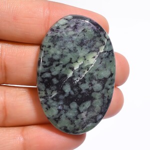 May include: A green and black oval cabochon gemstone with a speckled pattern.