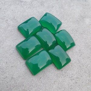 May include: Seven green gemstone cabochons cut into rectangular shapes. The gemstones are arranged in a staggered pattern.