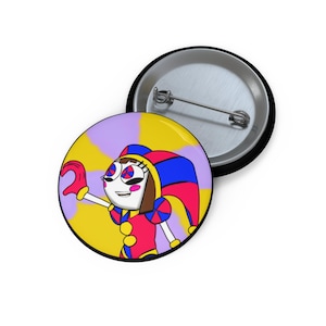 Könnte beinhalten: Ein runder Ansteckbutton mit einem Cartoon-Narren-Design. Der Narr hat ein weißes Gesicht, ein rot-blaues Outfit und einen passenden Hut. Der Hintergrund ist ein Wirbel aus Gelb und Lila. Ein weiterer Button ist sichtbar.