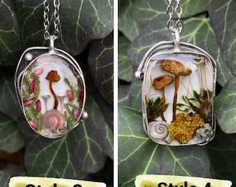 May include: Two silver necklaces with clear resin pendants featuring preserved mushrooms, moss, and other forest elements. The pendant on the left has pink flowers and a snail shell. The pendant on the right has yellow moss and a snail shell. The necklaces are labeled "Style 3" and "Style 4".