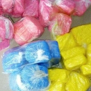 May include: A collection of colorful, individually wrapped, small, rectangular blocks. The blocks are pink, blue, and yellow.