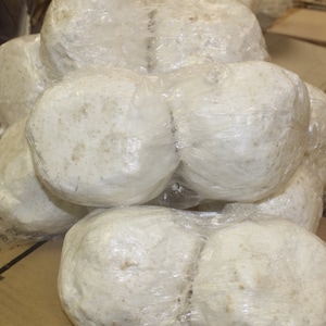May include: A close-up of several white, round objects wrapped in clear plastic. The objects are stacked on top of each other.