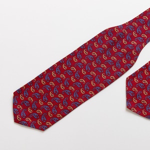 May include: A red tie with a paisley pattern in blue and yellow.