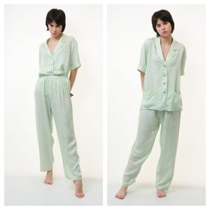 May include: A light green two-piece pajama set with a short-sleeved button-up top and matching pants. The fabric has a subtle pattern.