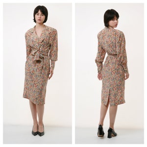 May include: A knee-length dress with a floral print in shades of red, yellow, and blue. The dress has a V-neckline, long sleeves, and a tie at the waist.