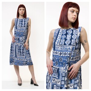 May include: A sleeveless midi dress with a blue and white geometric pattern. The dress has a scoop neck and a loose fit.