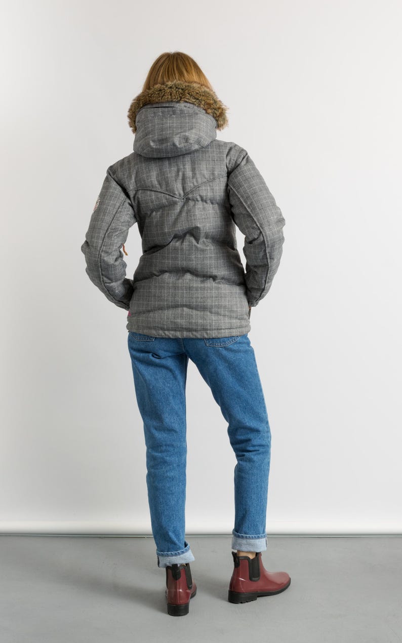 Puede incluir: Una chaqueta acolchada gris a cuadros con capucha forrada de piel, vaqueros azules y botines Chelsea burdeos. La chaqueta tiene un dise&ntilde;o acolchado y cierre de cremallera. Los vaqueros est&aacute;n doblados en los tobillos.