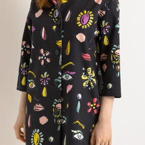 May include: A black button-up jacket with a colorful print of eyes, lips, flowers, and geometric shapes.