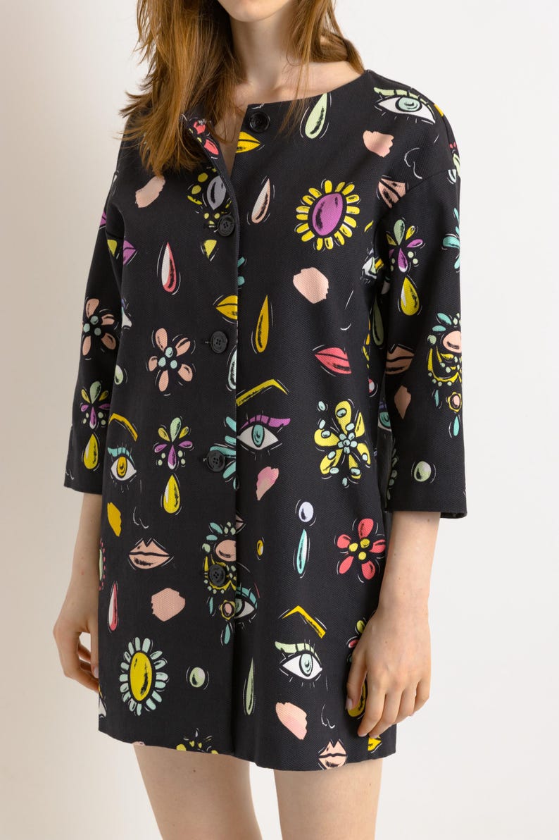 May include: A black button-up jacket with a colorful print of eyes, lips, flowers, and geometric shapes.