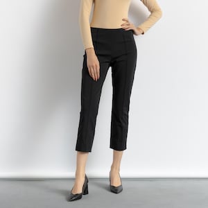 May include: A woman wearing black cropped pants and black heels.