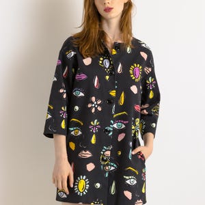 May include: A black button-up jacket with a colorful print of eyes, lips, flowers, and teardrop shapes. The jacket has a collar and three-quarter sleeves.