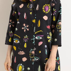 May include: A black button-up jacket with a colorful print of eyes, flowers, and teardrop shapes.