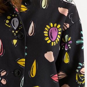 May include: A black button-up jacket with a colorful abstract print featuring eyes, flowers, and teardrop shapes.