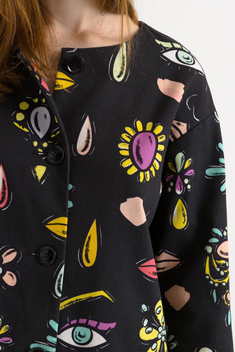 May include: A black button-up jacket with a colorful abstract print featuring eyes, flowers, and teardrop shapes.