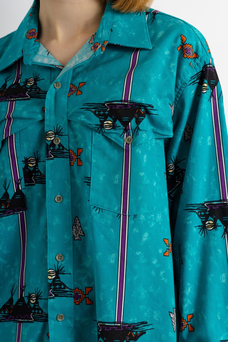 May include: A turquoise blue long-sleeved button-up shirt with a southwestern-inspired print featuring black, orange, and purple geometric designs.