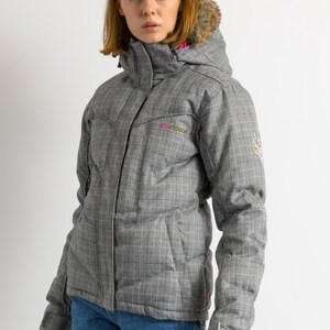 Puede incluir: Chaqueta de invierno gris a cuadros con capucha ribeteada de piel sint&eacute;tica. La chaqueta tiene un forro rosa y el nombre de la marca "Ripcurl" en rosa. Tiene cierre de cremallera y bolsillos. La chaqueta se lleva con vaqueros azules.