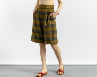 May include: High-waisted plaid shorts with a cuffed hem. The shorts are a mustard yellow and green plaid pattern.