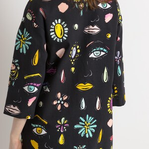 May include: A black short-sleeved dress with a colorful print of eyes, lips, flowers, and teardrop shapes.