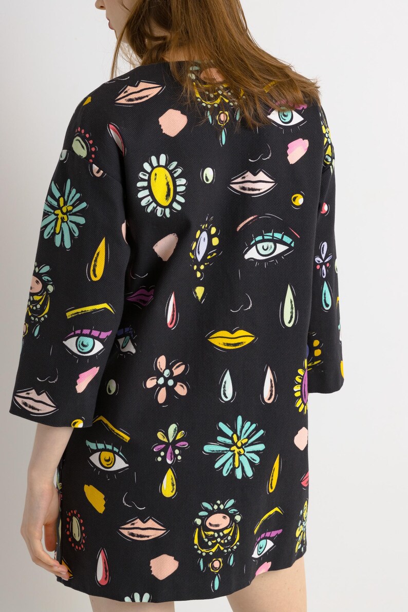 May include: A black short-sleeved dress with a colorful print of eyes, lips, flowers, and teardrop shapes.