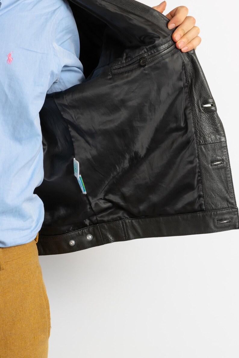 May include: Black leather jacket with a snap closure and a buttoned front. The jacket is unzipped and turned inside out, revealing a black lining.