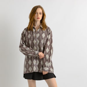 May include: A brown and white patterned long-sleeve shirt with a button-up front.
