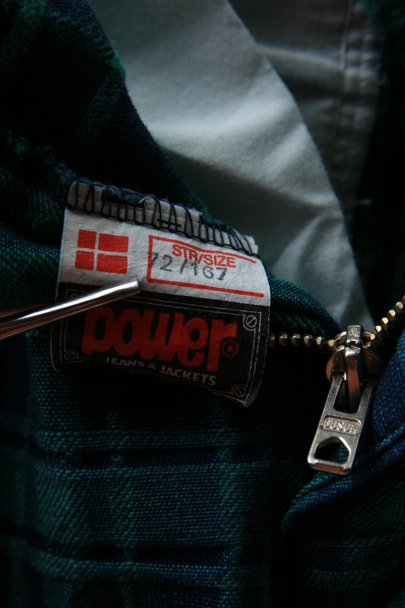 May include: A green and blue plaid jacket with a zipper closure and a Power Jeans & Jackets label. The label also includes a size tag that reads "Str/Size 22 M 67".